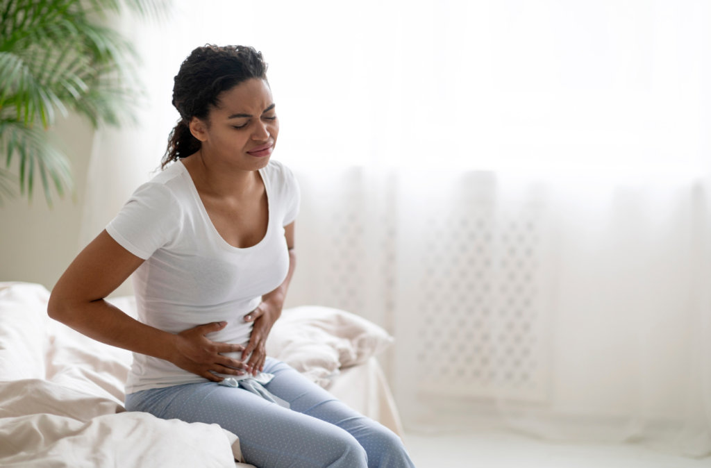 Mulher com expressão de dor segurando o abdómen – sinais de endometriose