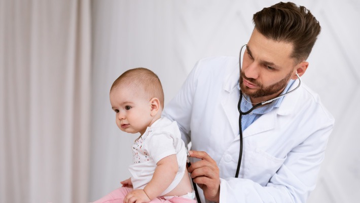 Médico examinando os pulmões de um bebé com suspeita de bronquiolite e dificuldades respiratórias.